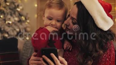 小美女妈妈戴着圣诞帽坐在沙发上，可爱的小男孩面带微笑